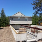 24x40ft cottage raised and rolled out of way. New foundation is completed and cottage is being rolled back onto the foundation.